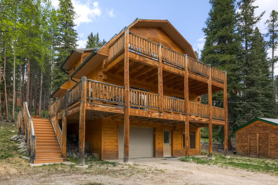 Three story house surrounded by pines.