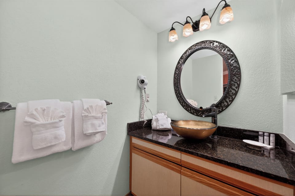 Step into your spa-like bathroom with elegant vessel sink, stylish round mirror, and plush towels artfully arranged just for you.