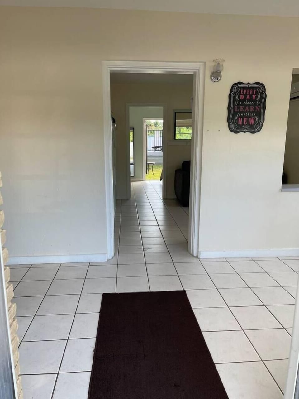 Standing in the front door, looking through the front room, the living/kitchen, the bedroom, and out to the back yard.