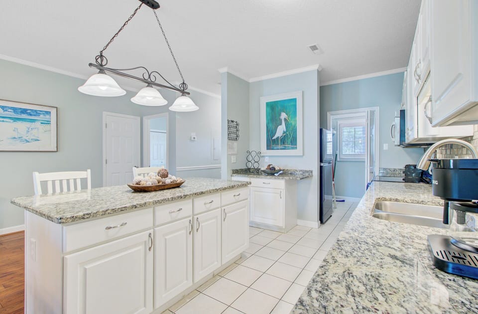 Cook with ease in your spacious coastal kitchen, featuring granite countertops and elegant lighting perfect for meal preparation.