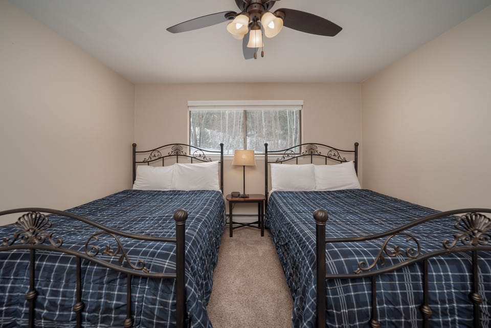 Rest easy in your comfortable twin bedroom with soft linens, gentle ceiling fan, and peaceful forest views.