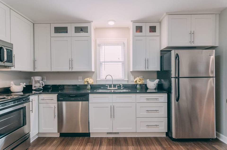 Bright white kitchen with stainless steel appliances  and granite 