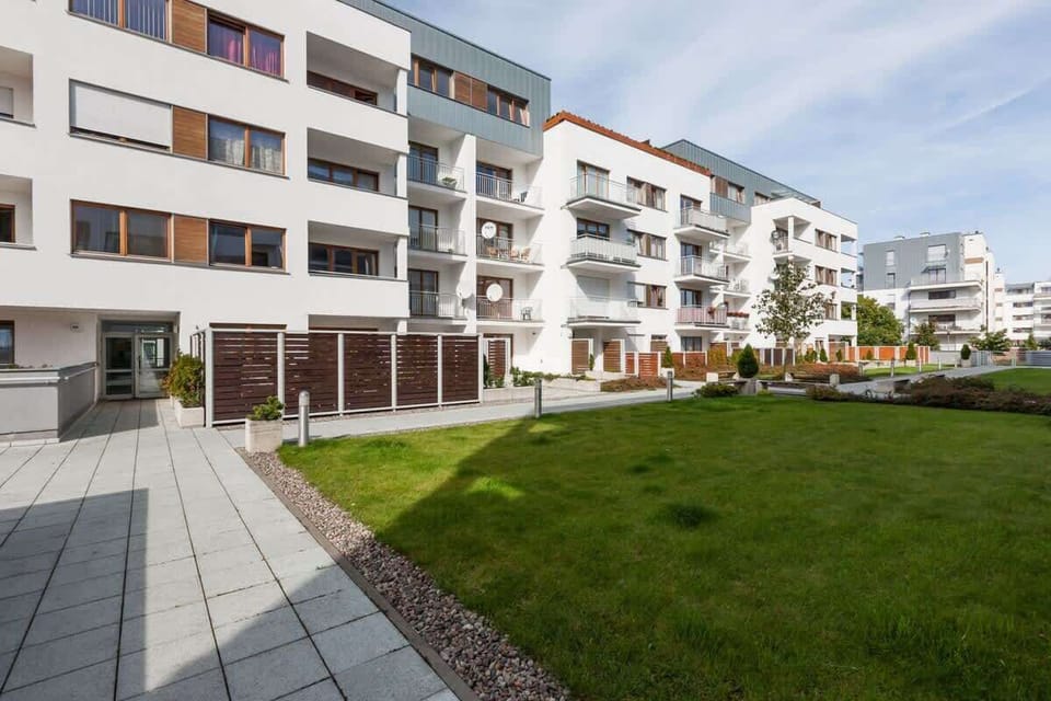The exterior of the apartment building, showcasing modern architecture and green spaces surrounding the property.