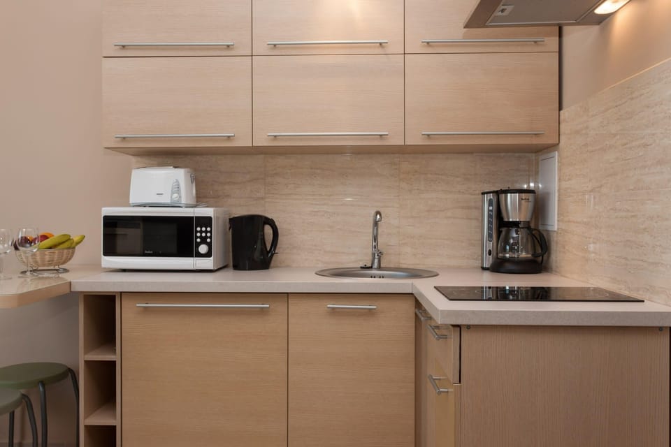 A closer view of the kitchen with light wood cabinetry, a microwave, a coffee maker, and various kitchen appliances. The countertop is clean and organized.