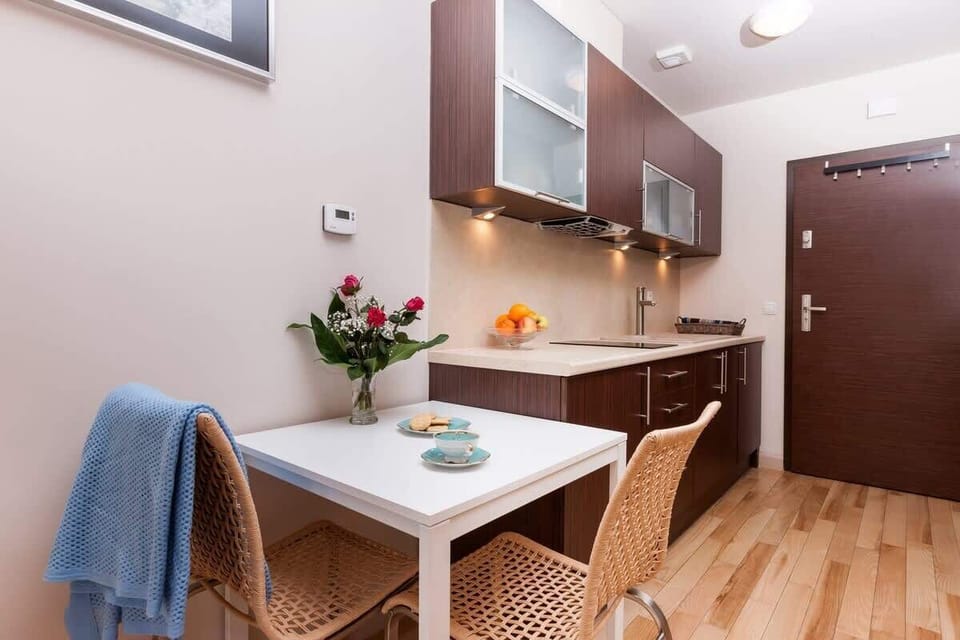 A small dining area with a table, chairs, and a flower vase. The space is cozy and integrated with the kitchen.