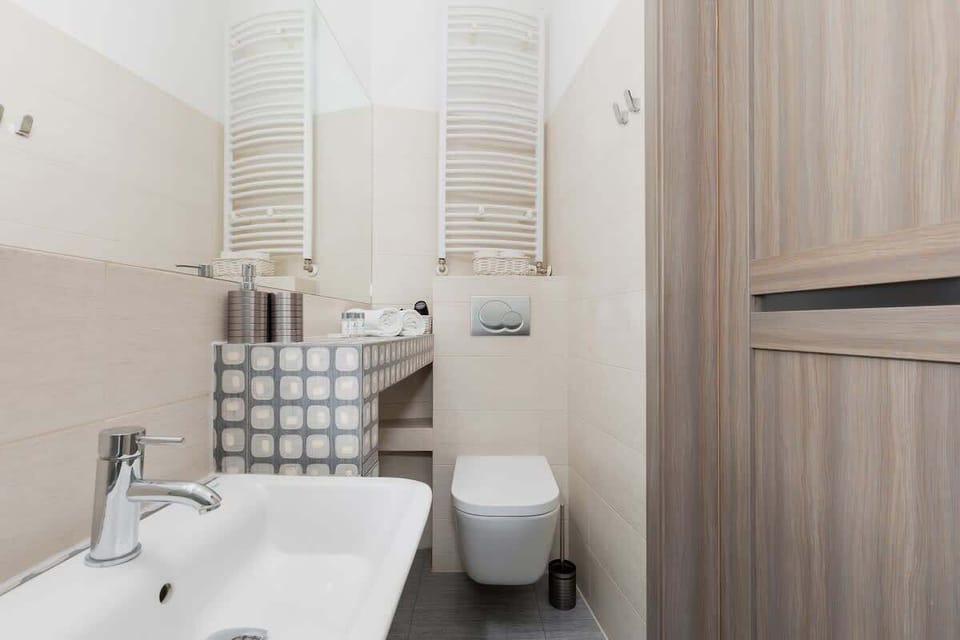 A sleek and functional bathroom with a modern white sink and WC. The space is minimal, with clean lines and white tiles, making it feel bright and spacious despite its compact size.