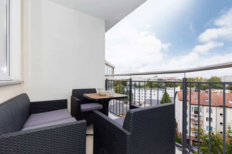 Another balcony with outdoor seating, providing a view of a sunny blue sky and rooftops from above.