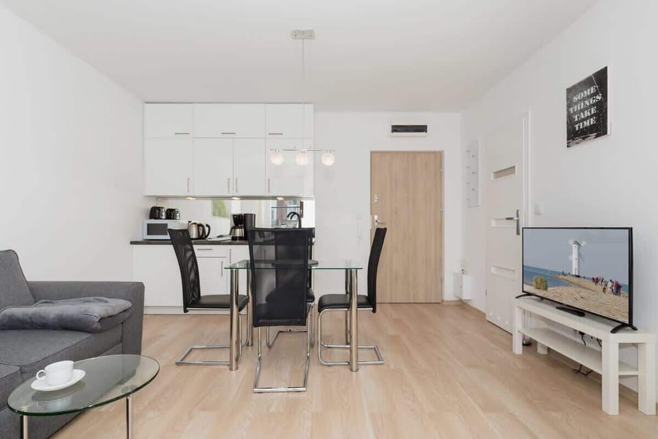 Spacious living room with television, coffee table, kitchenette, dining table and sofa.