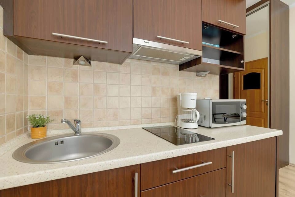 Close-up of the kitchenette with brown furniture. A microwave and a coffee machine stand on the countertop.