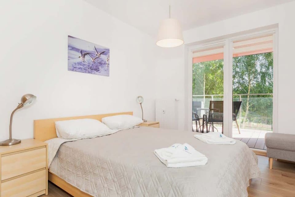 One bedroom with a double bed on which there is a grey bedspread. Next to it are bedside tables and a wardrobe.
