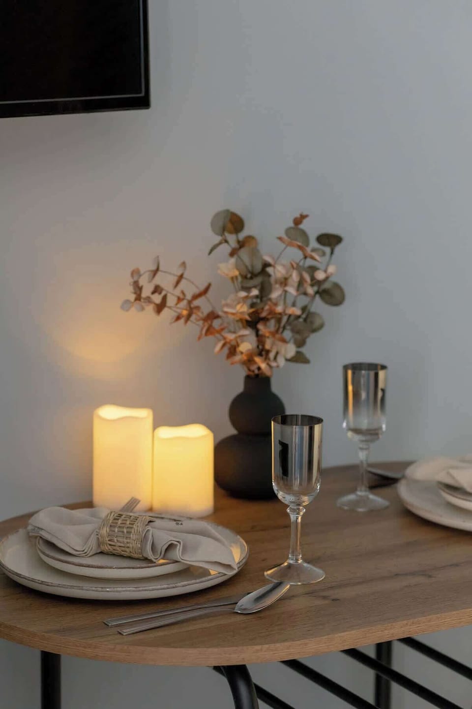A stylish decor arrangement on the dining table, featuring candles and a vase. This touch creates a welcoming dining setup.