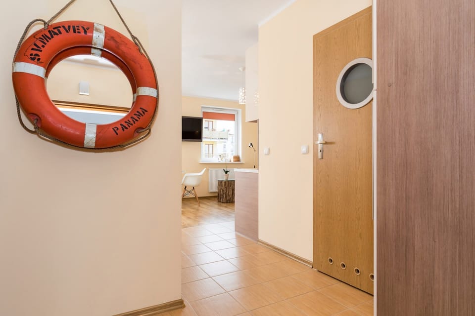 The entryway of the apartment, featuring a circular door design and a mounted life preserver as a quirky decorative touch.