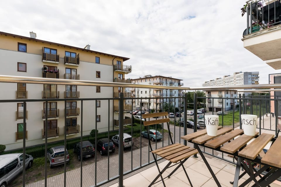 The view from the balcony looking out onto other buildings within the residential complex, with parking spaces and greenery visible.