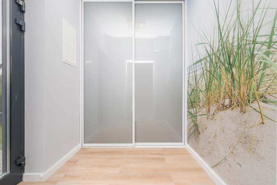 A bright hallway with a large wardrobe and light wooden floors and access to many rooms, creating a welcoming transition area in the house.