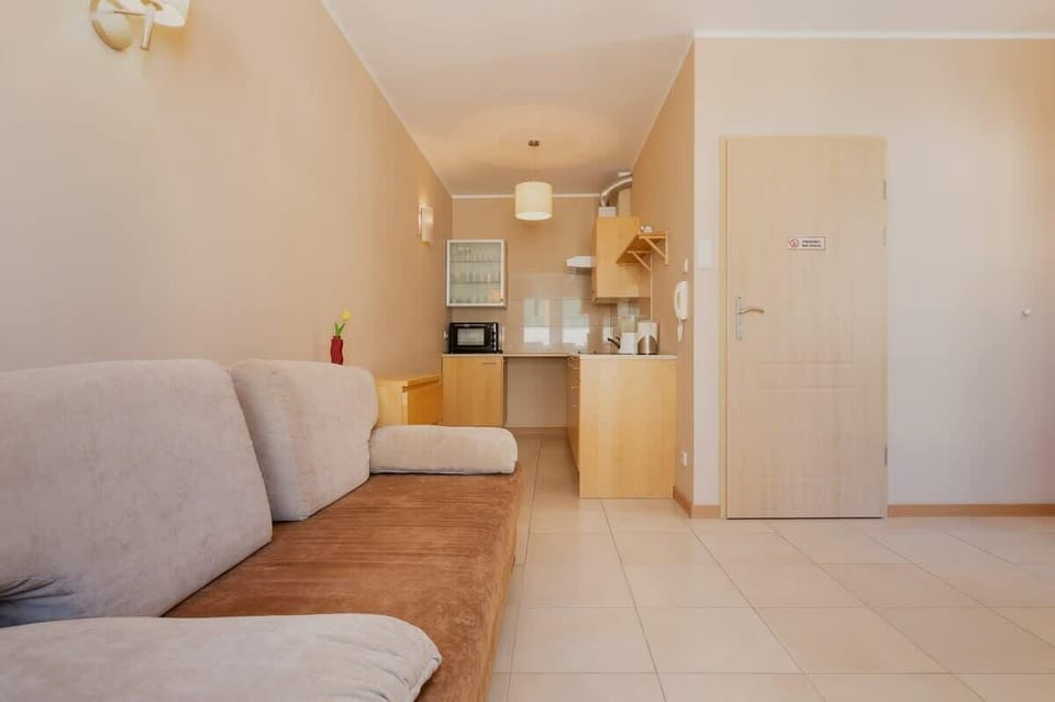 A living room with a sofa and soft lighting. The open layout flows into a hallway, adding to the apartment's sense of space.
