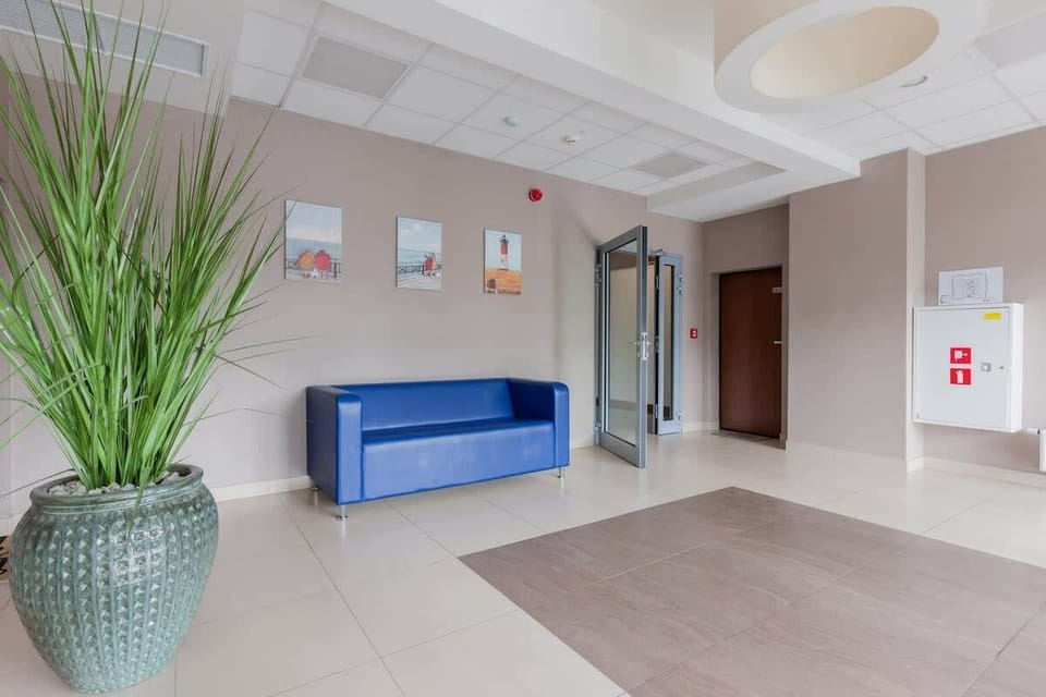 A bright, modern entryway or lobby area with a plant, seating area, and neutral wall decor. The space feels welcoming and open, with contemporary finishes.
