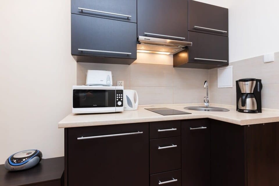  view of the modern kitchen area with dark wood cabinets, a microwave, stovetop, coffee machine, and various appliances, showcasing a fully equipped setup.