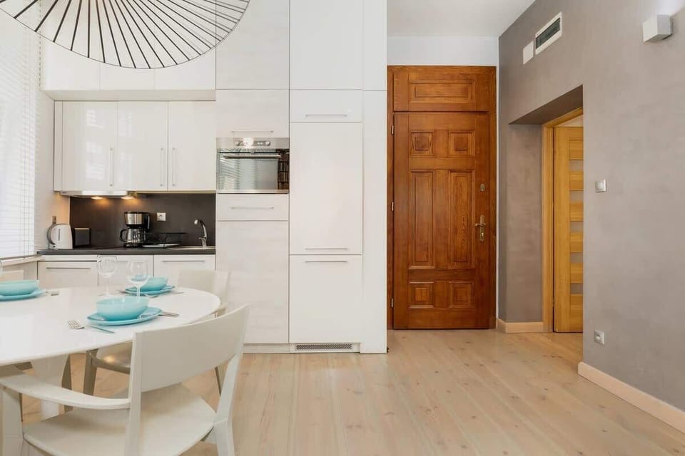 A view of the dining area in the open-plan living space, with a white round table and chairs. The room is spacious and filled with natural light from large windows.