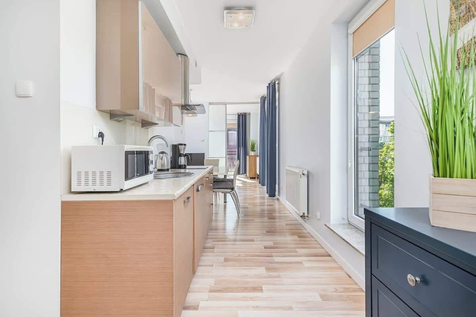 Stylish living room with functionally equipped kitchenette, dark blue double sofa bed and exit to the furnished balcony.