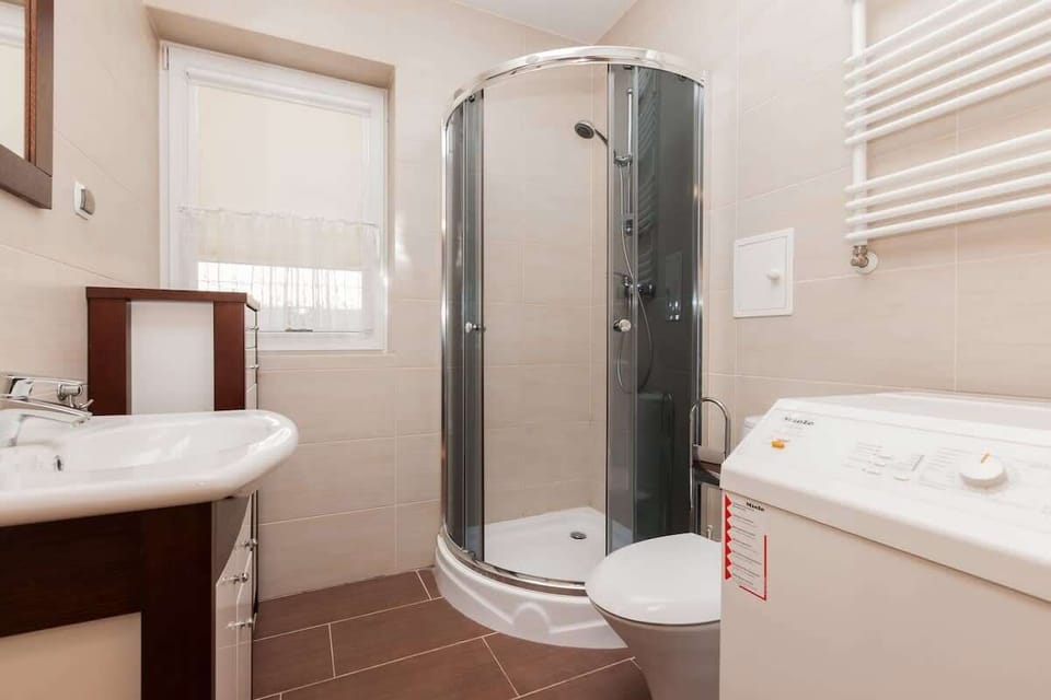 Bathroom with shower cubicle in contemporary style. The room has a washbasin and a toilet, all in bright, warm colours.