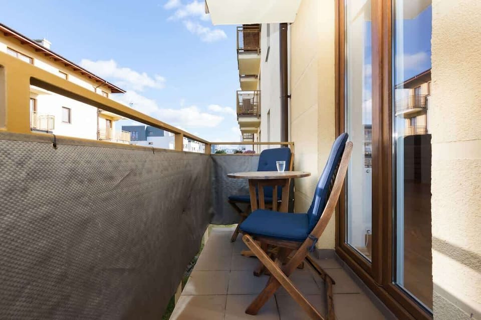 
Balcony overlooking the neighbouring buildings. It contains a chair and a table, ideal for relaxing outdoors. The balcony is partially covered by a balustrade.