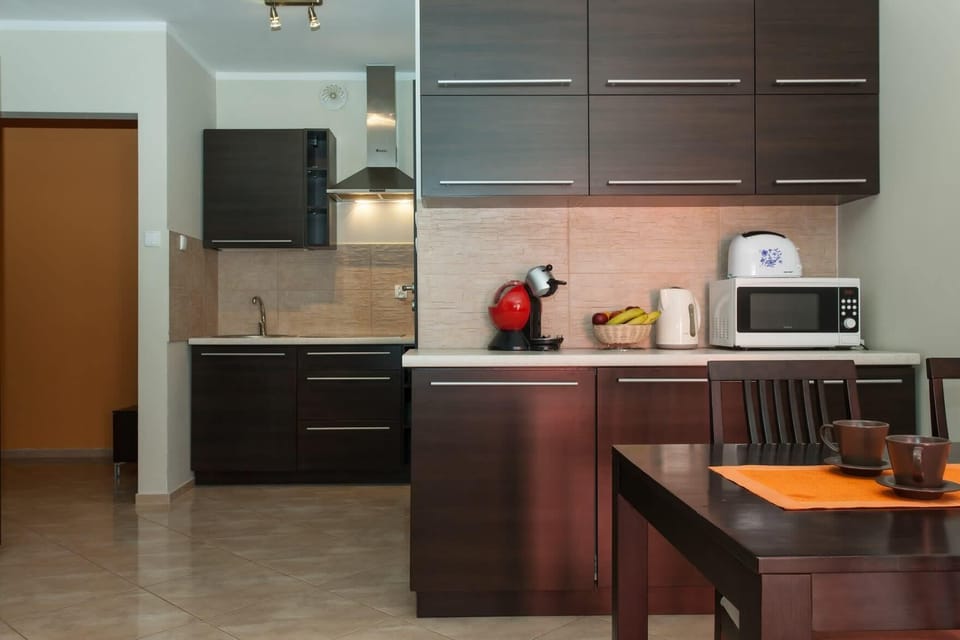 A close-up view of the modern kitchen, with dark wooden cabinetry and essential appliances like a kettle and microwave. A sleek countertop provides a workspace for cooking.