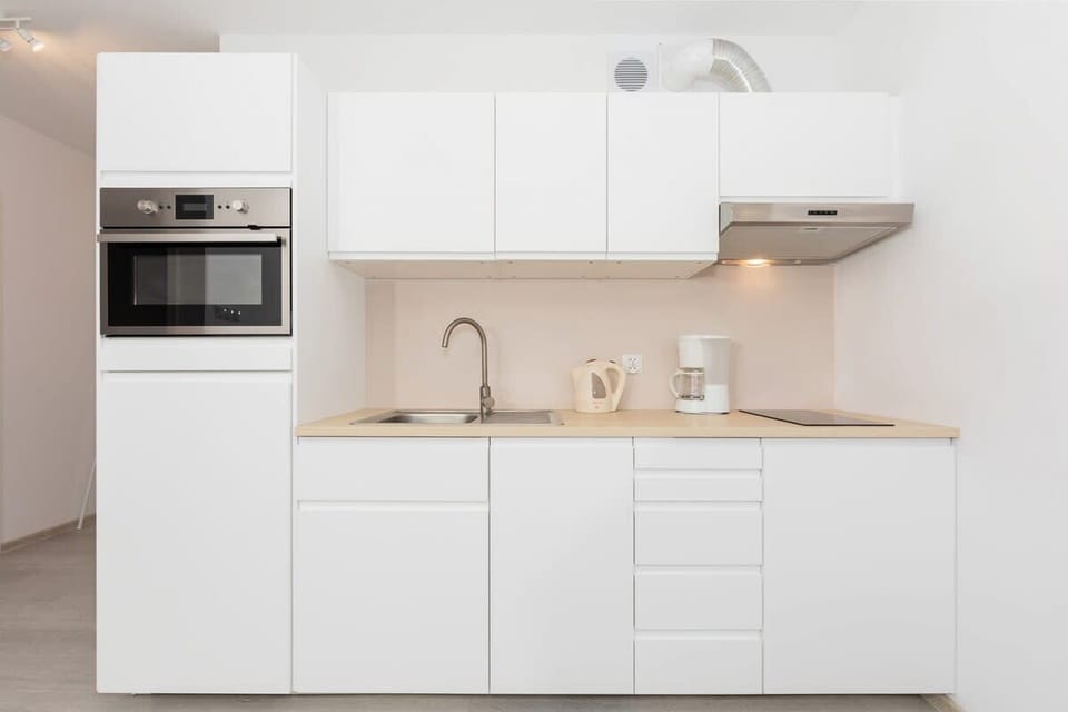 Functional kitchenette with white furniture and appliances.
