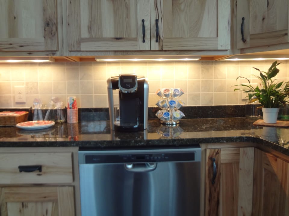 granite counters under cabinet lighting, Keurig coffee maker, lots of cups