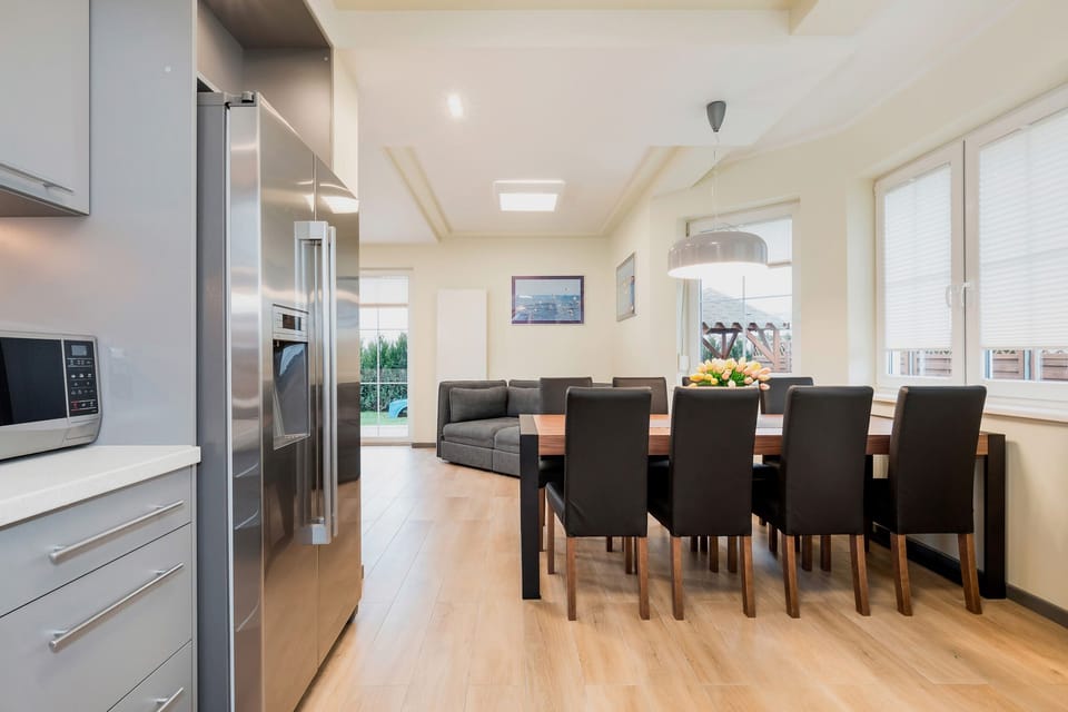 A dining area connected to a living room, featuring a wooden table with four chairs and an open, spacious design.