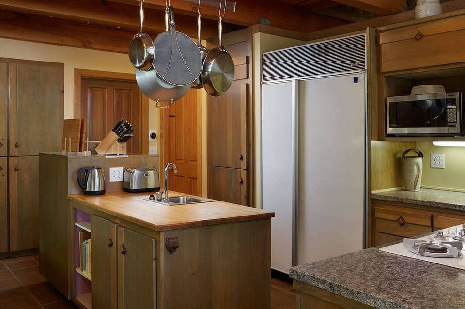 Center island counter with sink and large subzero refrigerator.