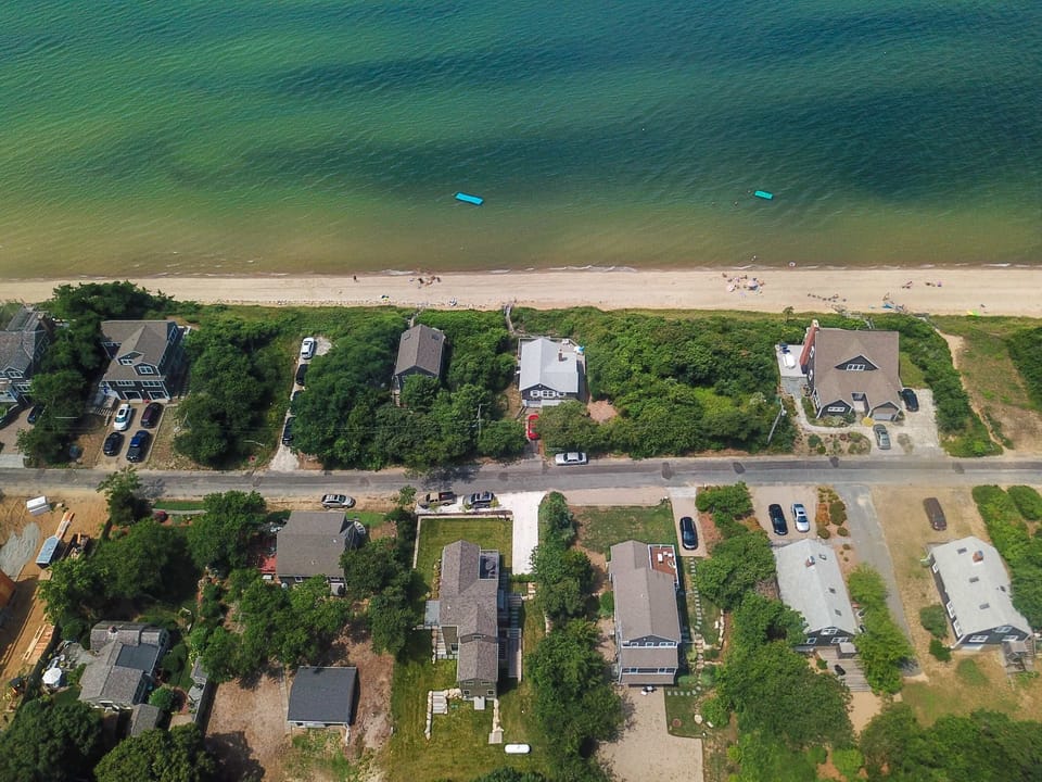 drone view of neighborhood and property's proximity to the bay/ beach
