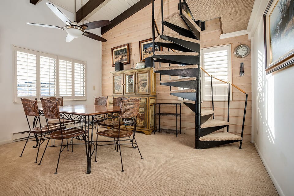 Your charming dining space features a rustic table beneath exposed beams, with a unique spiral staircase adding character to your stay.