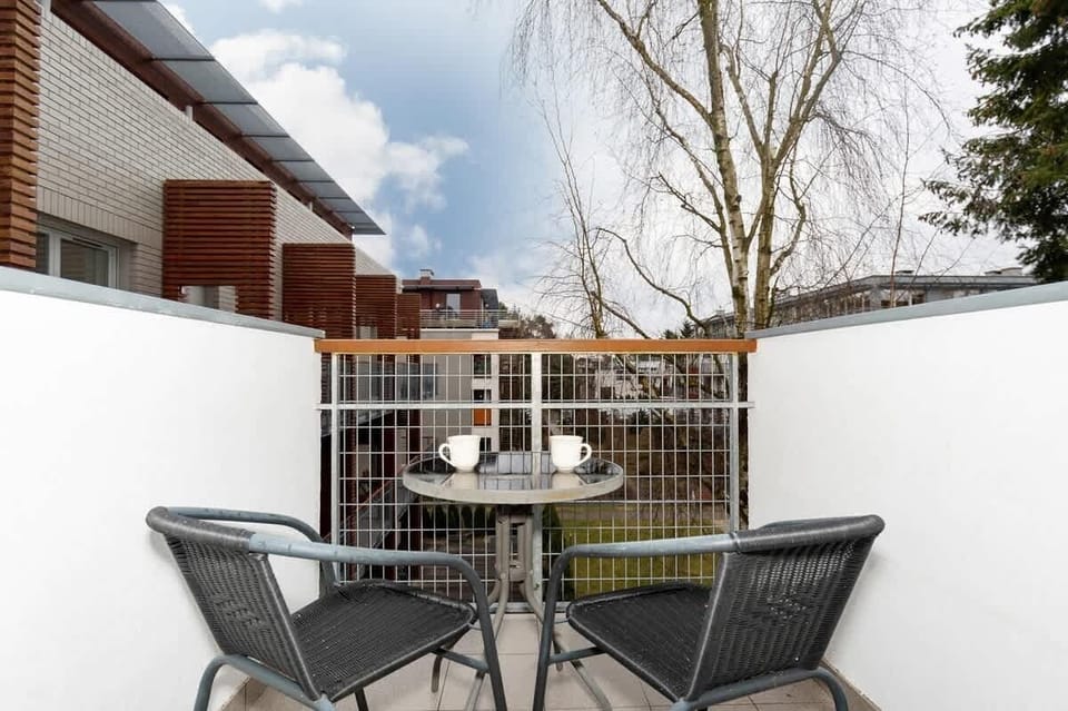 A balcony setup with a small round table and two chairs, overlooking a scenic outdoor area.
