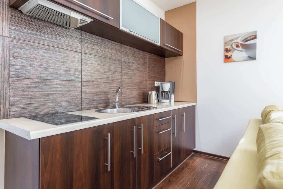 A compact kitchenette with dark brown cabinets and modern appliances, creating a sleek and functional cooking area.