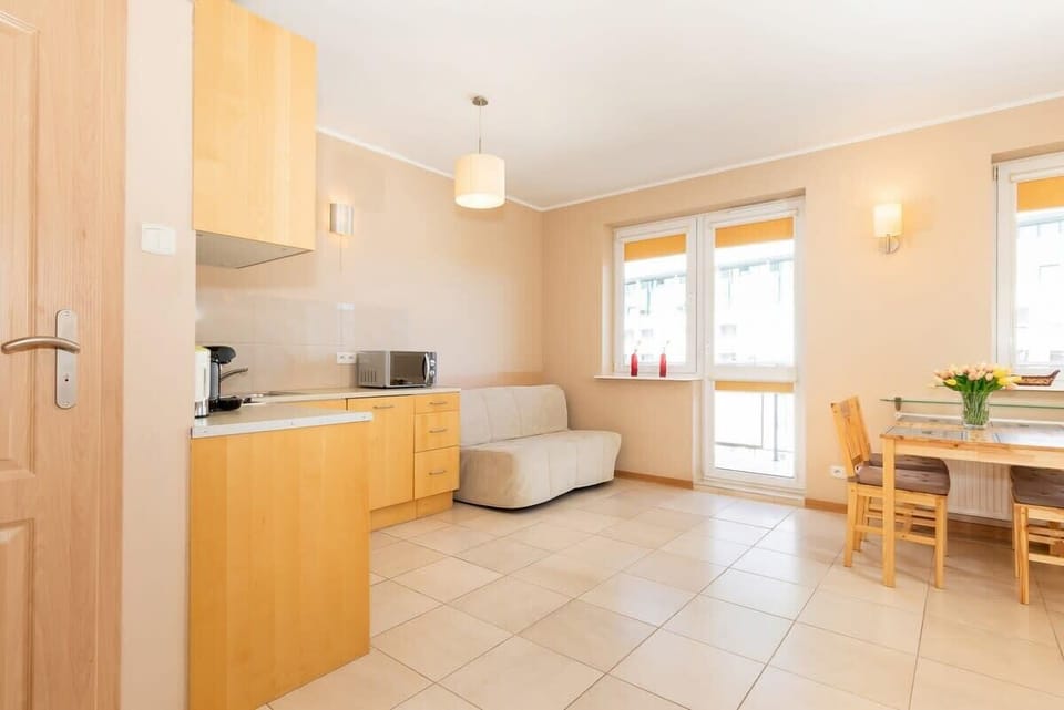 Another living room angle, showing a sofa, coffee table, and a wooden dining table. The room is spacious and filled with natural light.