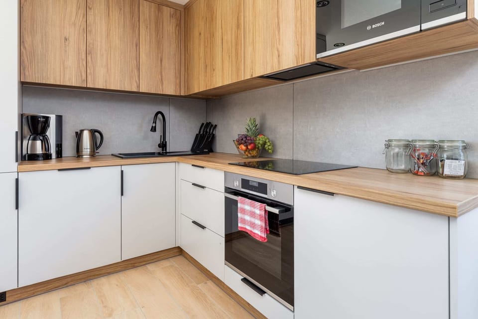A stylish kitchen corner with minimalist wooden cabinets, modern appliances, and a clean, white countertop.