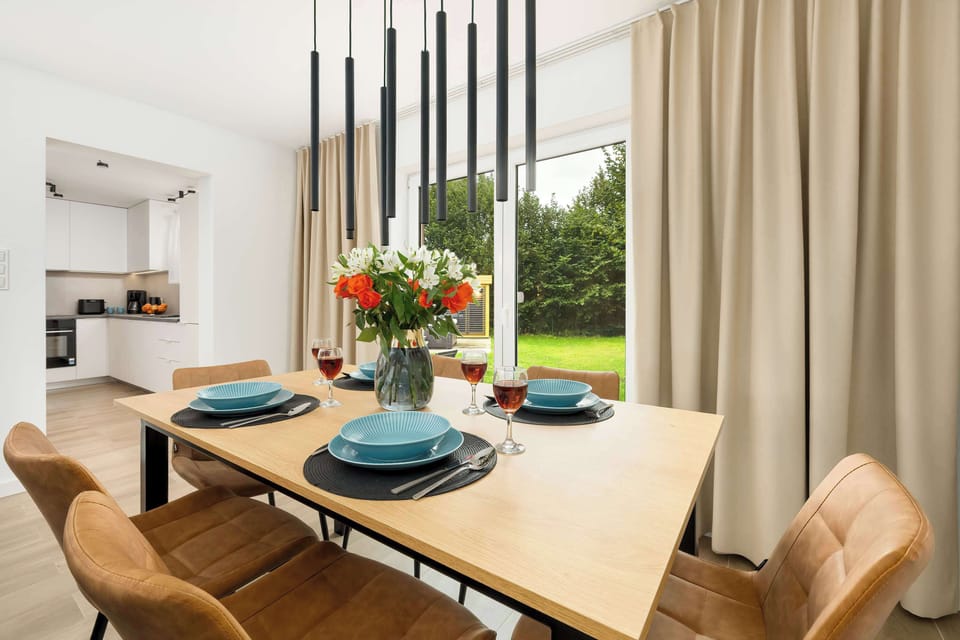 The wooden table set with tableware and fresh flowers invites guests to share meals in the bright dining area.