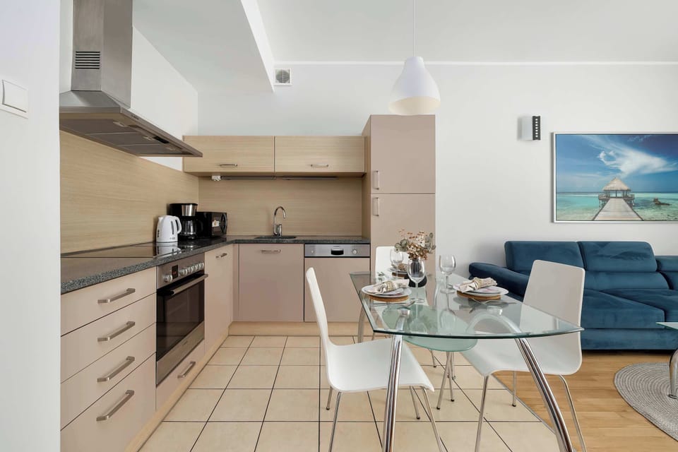 A bright kitchen and dining area with modern cabinets and a glass table. The space feels clean and functional for everyday meals