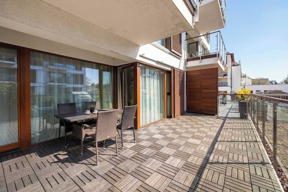 A long balcony with outdoor furniture and tiled flooring. It offers a great place to enjoy fresh air.