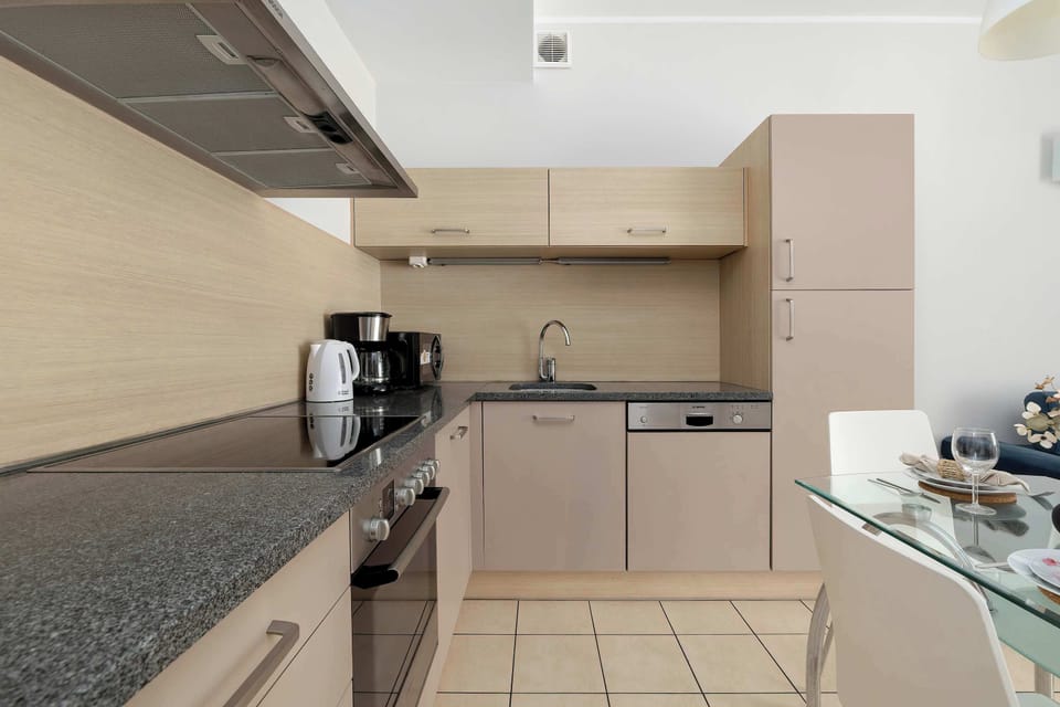 A compact kitchen with appliances and tiled flooring. It looks practical and easy to maintain.