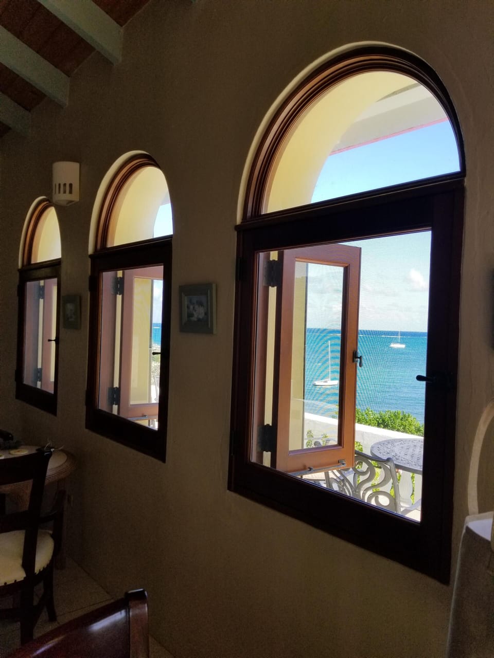 View from living room screened windows overlooking front deck, pool, sea + beach