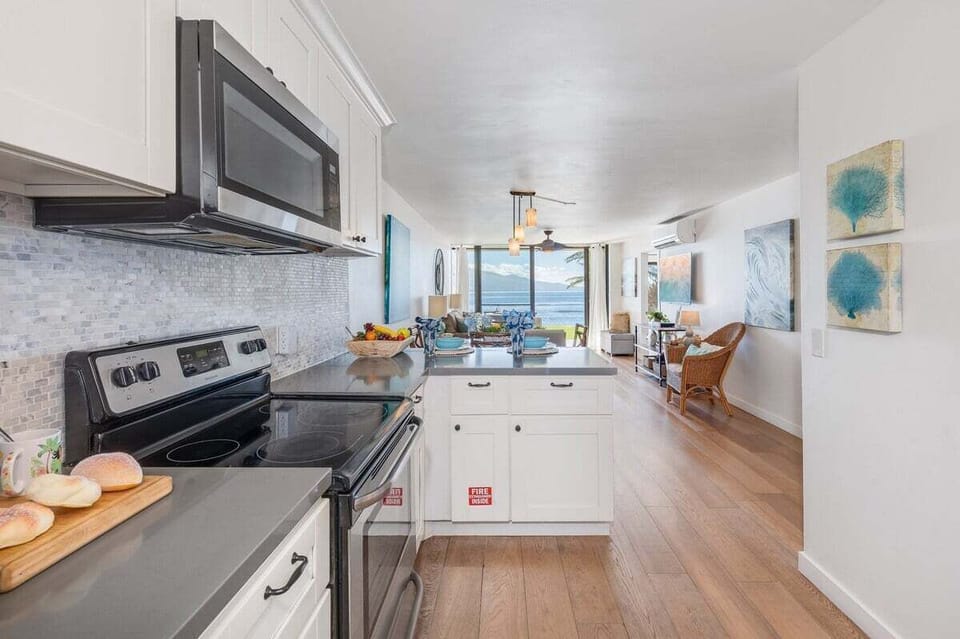 A stylish kitchen with crisp white cabinets and stone backsplash, perfect for meal prep with a view