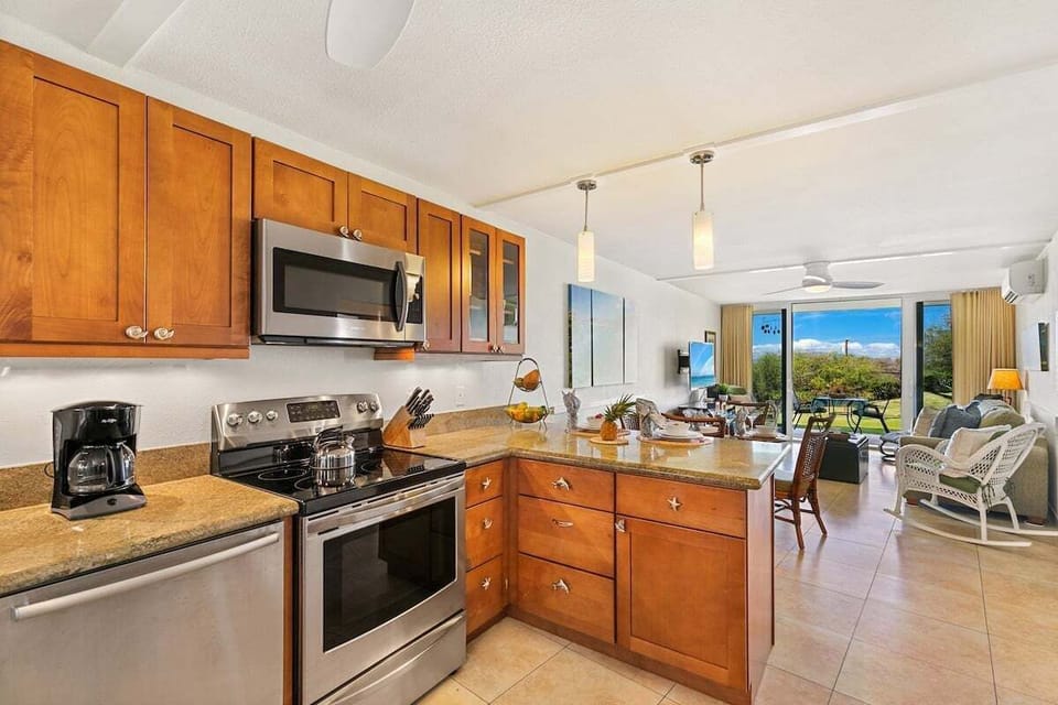 Fully equipped kitchen with stainless-steel appliances, wood cabinetry, and a spacious breakfast bar flowing seamlessly into the open‑concept living area.