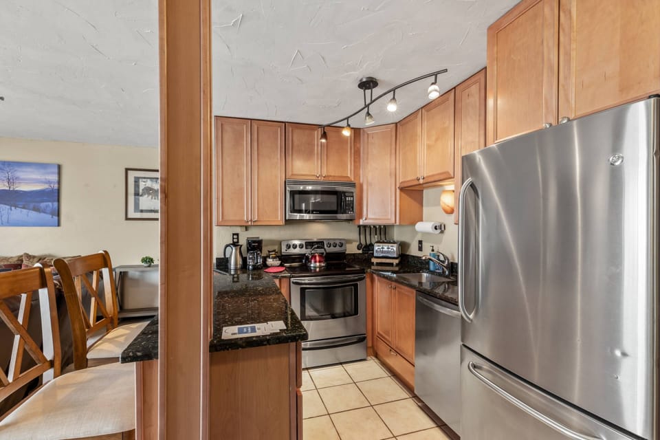 Fully equipped kitchen with stainless steel appliances, granite countertops, and warm wood cabinetry—everything you need for home-cooked meals or a qu