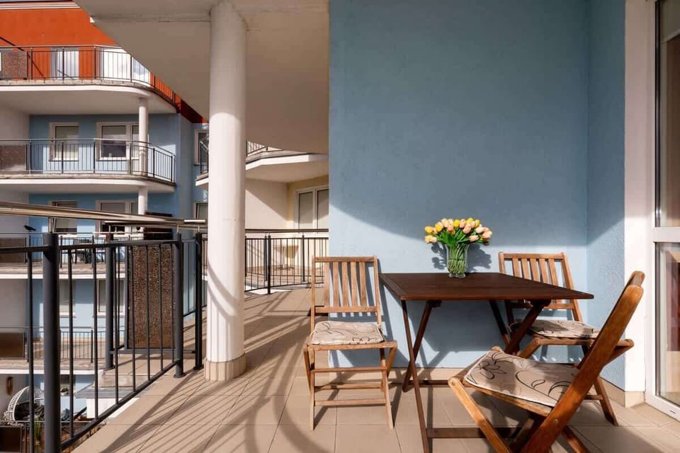 A small balcony with a table and two chairs, perfect for morning coffee. The table has a small potted plant for a touch of greenery.