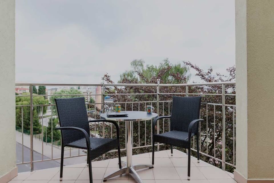 Spacious balcony with views of the surrounding area and table and chairs.