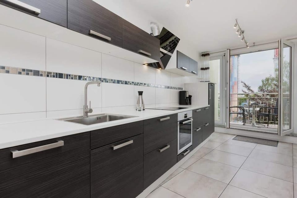 Kitchen with dark melbls and oven. From the kitchen you can access the balcony.