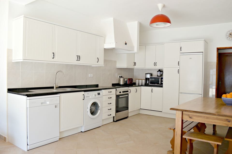 Part view of large fully fitted kitchen with granite working tops. 