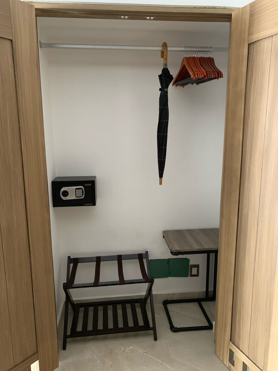 Hallway closet with luggage rack, umbrella, table, hangers, and security safe.
