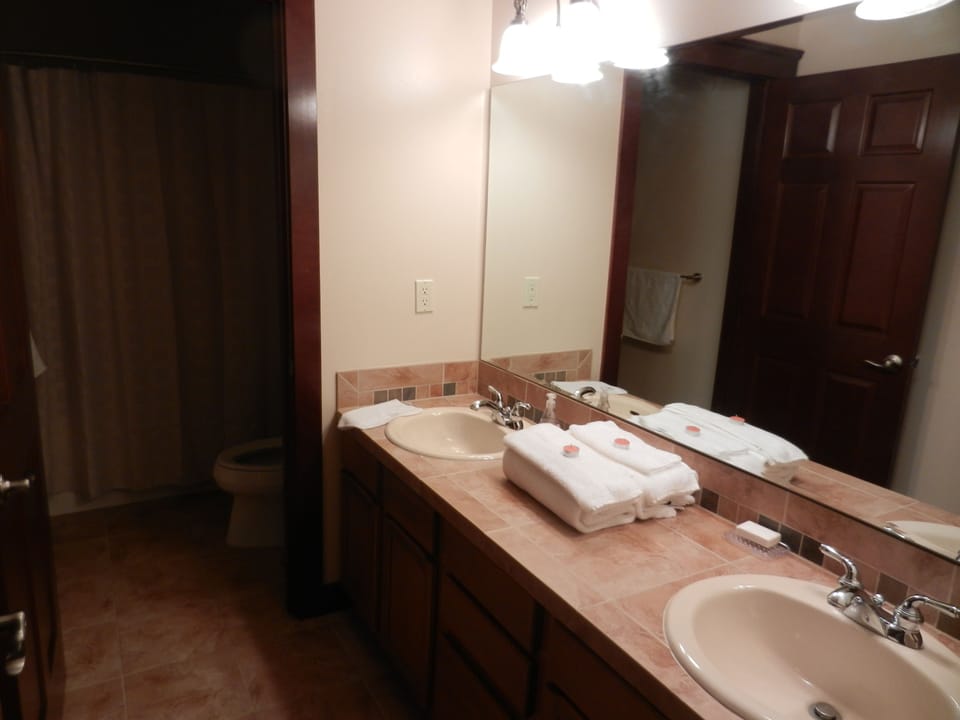 Upstairs bathroom with 2 sinks and a tub with shower and toilet.
